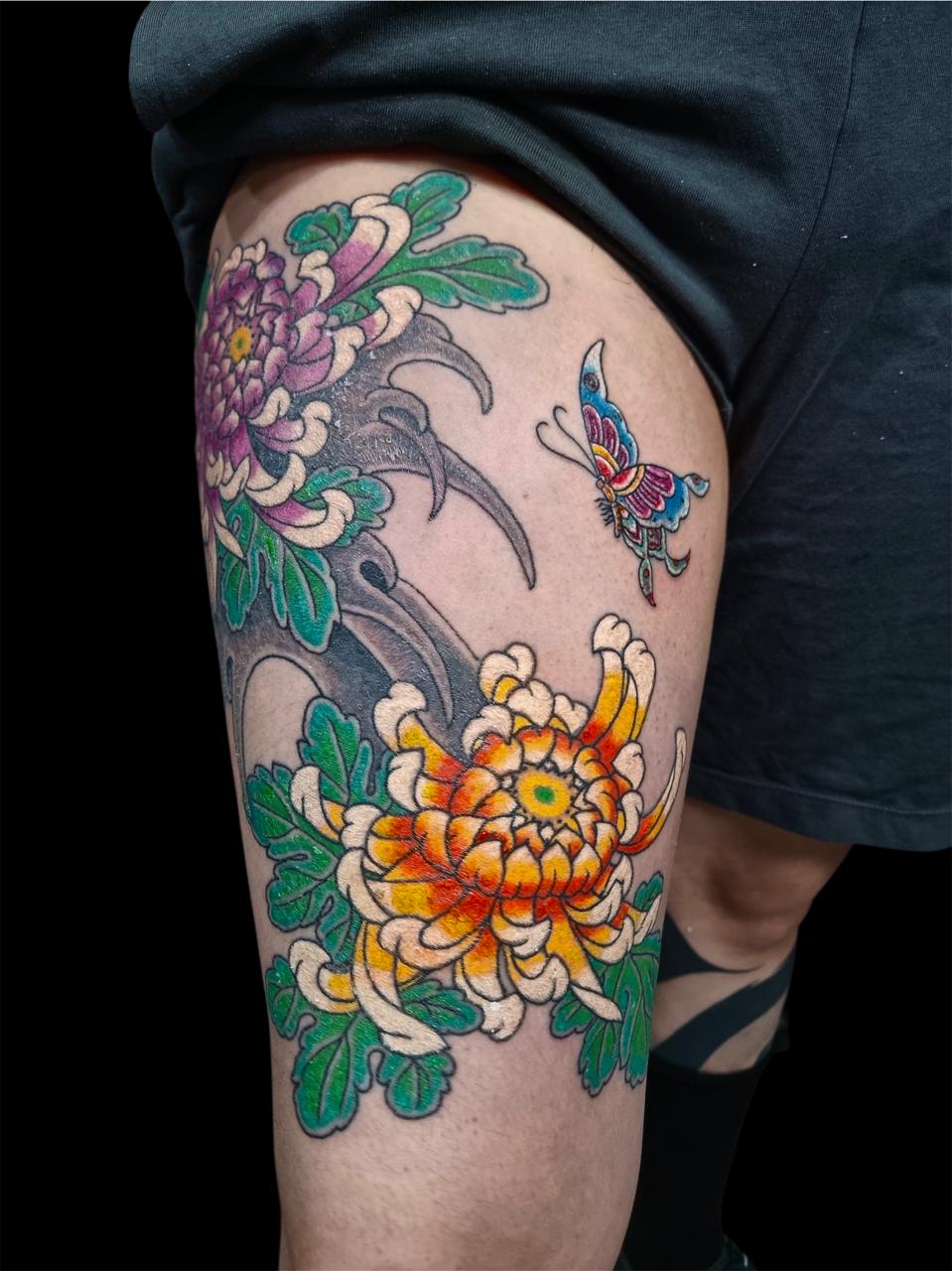 Tatuagem japonesa de crisântemos coloridos na coxa