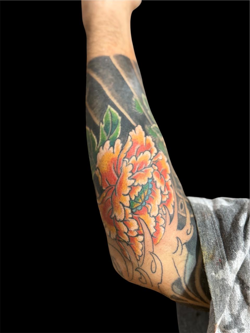 Tatuagem japonesa de peônia alaranjada no antebraço